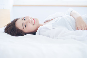 Fototapeta premium beautiful Asian woman smiling on bed
