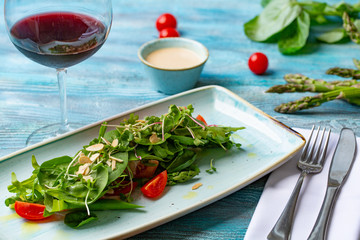 Fresh salad with tomatoes and mixed greens. arugula, mesclun, mache on wooden background. Healthy food.
