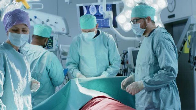 Diverse Team of Professional surgeon,  Assistants and Nurses Performing Invasive Surgery on a Patient in the Hospital Operating Room. Shot on RED EPIC-W 8K.