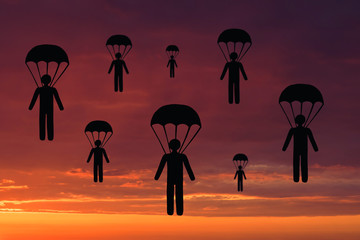 Naklejka premium Silhouettes of paper men with parachutes against the background of the sky and sunset. Concept of team and sport
