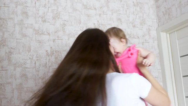 mom twists child in his arms, happy baby laughs
