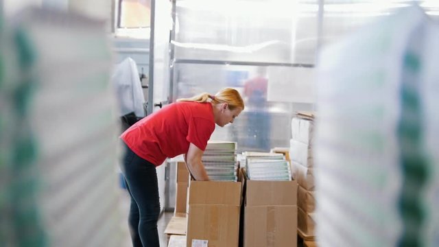 Female worker puts printed magazines in a box in the typography