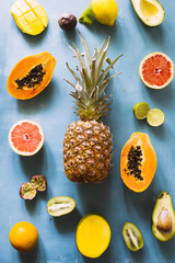 Summer fruit background, top view of summer fruit ,wooden background, papaya, mango, pasion fruits, cantalupe, strawberries, blueberries, raspberries over a gray concrete backdrop, natural light.