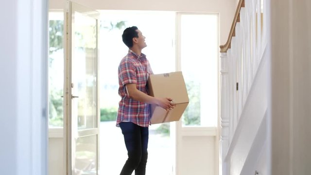 Portrait Of Young Man Carrying Box Into New Home On Moving Day Shot In Slow Motion