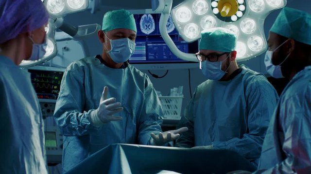 Diverse Team of Professional Doctors Performing Invasive Uses Augmented Reality Technology on a Patient in the Hospital Operating Room. Shot on RED EPIC-W 8K.
