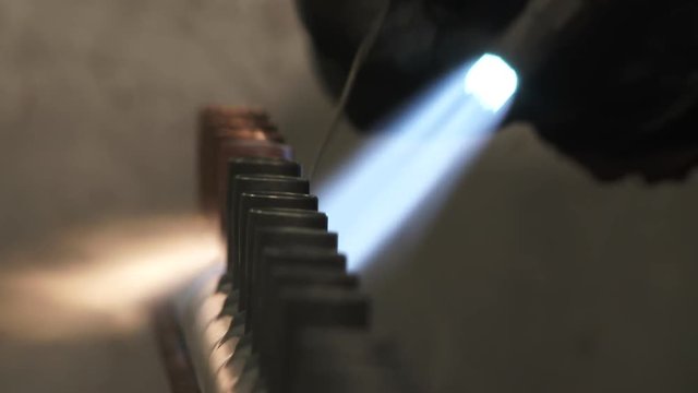 Close up on blow torch fusing copper parts together with solder.