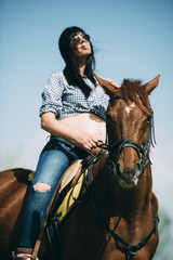 Pregnant woman with horse in the green field