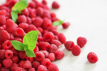 Fresh organic raspberries with mint leaves. Fruit background with copy space. Summer and berries harvest concept. Vegan, vegetarian, raw food.