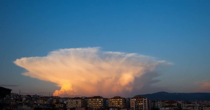 Cumulonimbus Capillatus clouds with some cumulus clouds while getting dark and sun going down.