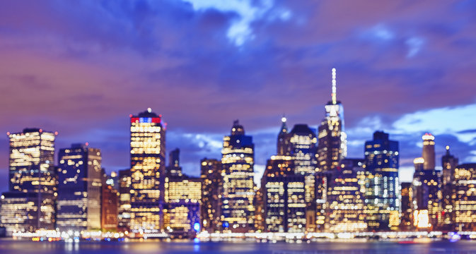 Blurred color toned Manhattan waterfront skyline at night, urban background, New York City, USA. 