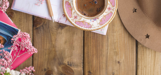 A cup of fragrant coffee and a notepad for notes. Good morning . Wooden background. Place for text. Vertical photo. Banner