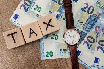 Tax wooden cubes with clock on euro bills