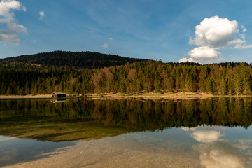 Fototapeta premium A alone hut in front of a forest with great reflections at Ferchensee