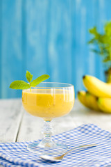smoothies with banana and mint, blue napkin and wooden background. Place for text