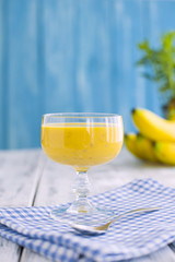 smoothies with banana, blue napkin and wooden background. Place for text