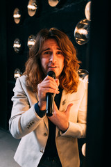 men singer with long hair, with microphone on the stage