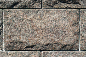 rough granite rectangular block in the composition of masonry wall