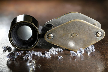 brilliant cut diamonds with folding magnifier on wooden background