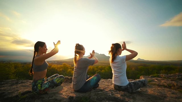 A group of girls at sunset are engaged in yoga. Slow motion