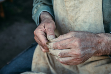 Potter works with clay, craftsman hands close up, kneads and moistens clay