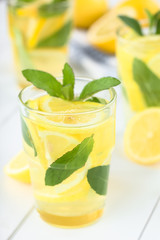 Fresh homemade lemonade with mint leaves (Selective Focus, Focus on the front of the rim of the first glass)
