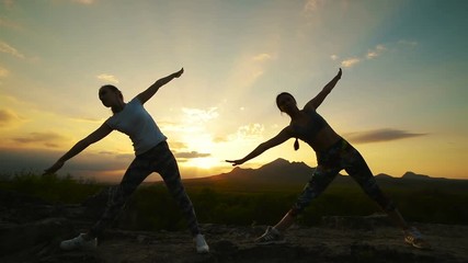 a group of girls doing yoga at sunset in the mountains. Slow motion