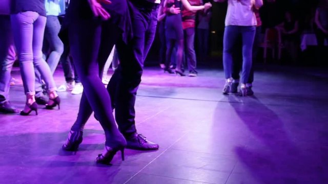 A guy and a girl dancing in a night club under Latin American rhythms and dance forms. The guy leads the girl. Night, indoors, party, disco lights on the dance floor a lot of people