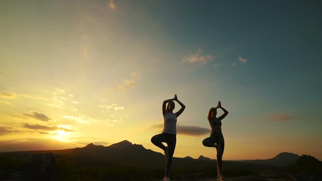 a group of girls doing yoga at sunset in the mountains. Slow motion