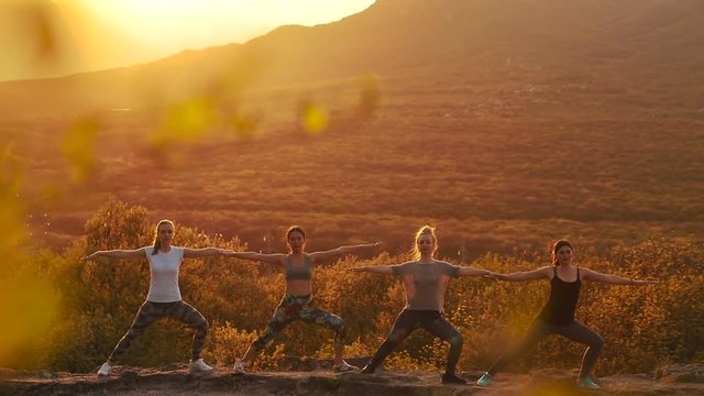 a group of girls doing yoga at sunset in the mountains. Slow motion