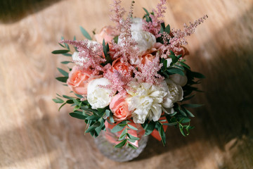 Wedding bouquet of white peony and pink roses wooden table. Lots of greenery, modern asymmetrical disheveled bridal bunch