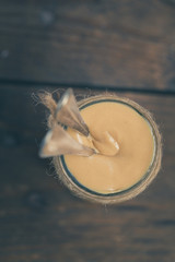 A jar of homemade raw organic almond butter with a fresh salty almonds on the wood board on the brown old rustic wooden background