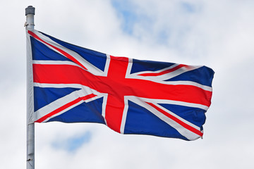 United Kindom of Great Britain and Northern Ireland national flag aka Union Jack on cloudy sky.