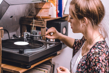 young woman putting on a vinyl record at home