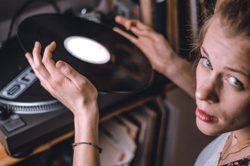 young woman putting on a vinyl record at home