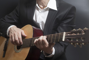 Fototapeta na wymiar Man in black suit with acoustic classic guitar