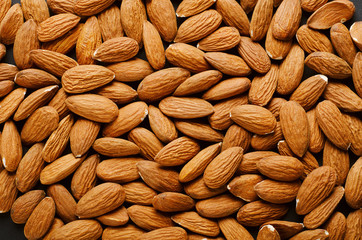 Pile of almonds on the surface. Close-up, top view, texture. Healty food, vegetarian.