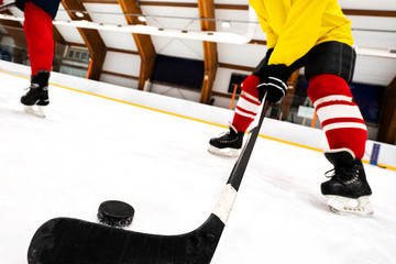 The hockey player is holding a stick in the hands directed to the puck. Winter Sports games.