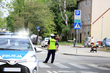Policjant z samochodem służbowym na skrzyżowaniu ulic w centrum miasta Opole.