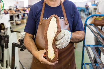 Close-up of shoemaker's hand holding a handmade shoe.