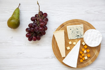 Tasting cheese with fruits on white wooden background. Food for wine, top view. Space for text. Flat lay. From above.