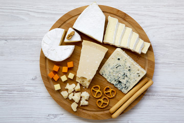 Tasting delicious cheese with  walnuts, bread sticks and pretzels on wooden background, top view. Food for romantic. From above. Flat lay.