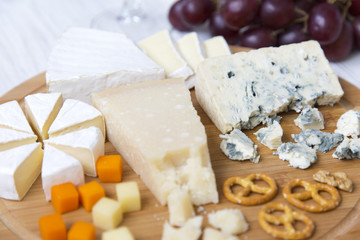 Tasting cheese with wine, grapes and pretzels on wooden background. Food for romantic. Closeup.