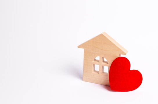 Wooden house with a red heart on a white background. Love nest, love relationships. Buying a house with a young family. Affordable housing. Family psychology, strong relations. Love and offspring.