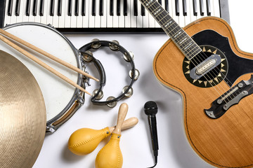 a group of musical instruments including a guitar, drum, keyboard, tambourine.