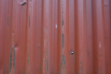 Corrugated metal sheet serves as a fence, view horizontal to vertical stripes