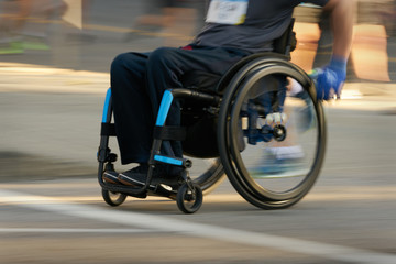 Fototapeta na wymiar Racing in a Wheelchair. Competitor using a wheelchair in a race. Motion blur.