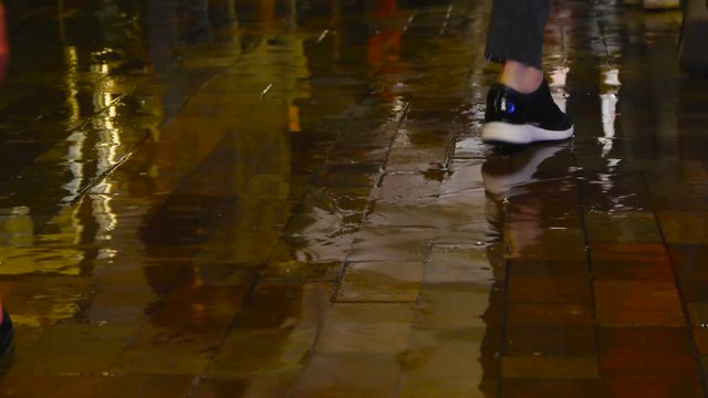 Feet walk through puddles on rainy day at outdoor, people enter a puddle