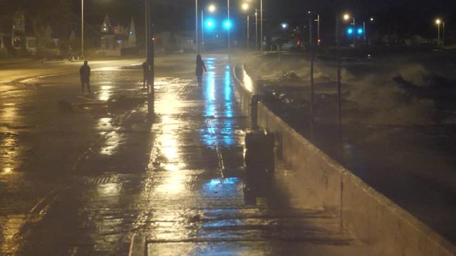 People Watch As Waves Crash Over A Seawall During Storm