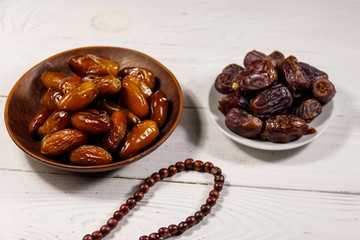 Dates fruit and rosary on white wooden table