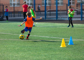 Obraz premium boys football players practice dribbling, kickson soccer training on the field in the summer